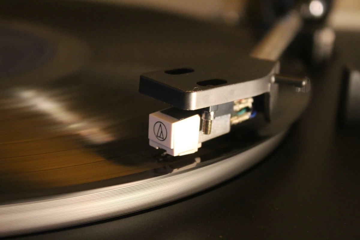 Primer plano de la aguja y la cápsula de un tocadiscos apoyadas sobre un vinilo