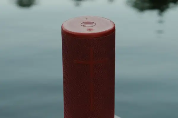 Altavoz Bluetooth portatil rojo junto a un lago