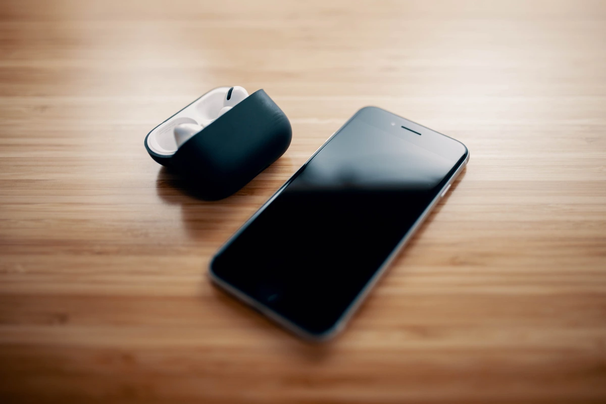Auriculares true wireless en su estuche de carga junto a un movil