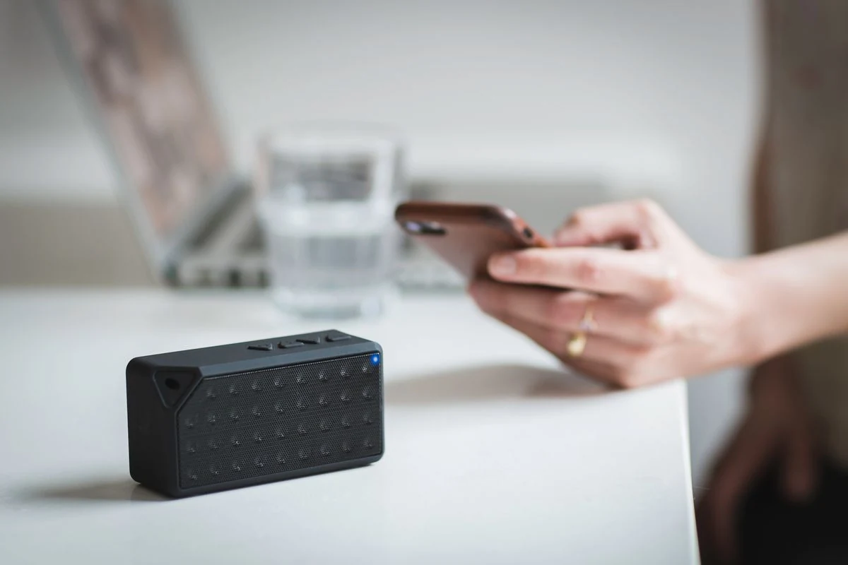 Persona conectando el móvil a un altavoz Bluetooth sobre una mesa