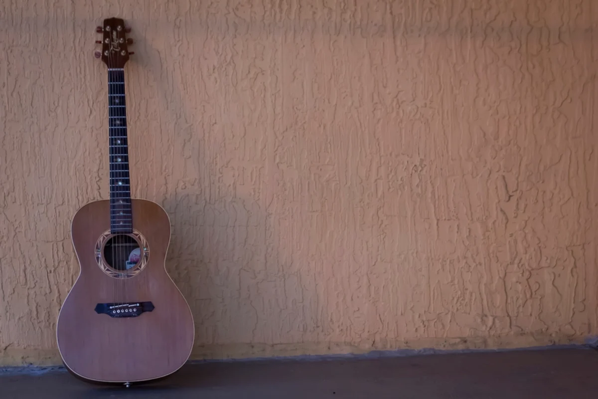 Una guitarra acústica apoyada en una pared