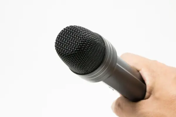 Microfono inalambrico de mano sujeto con la mano, sin cable, sobre fondo blanco neutro