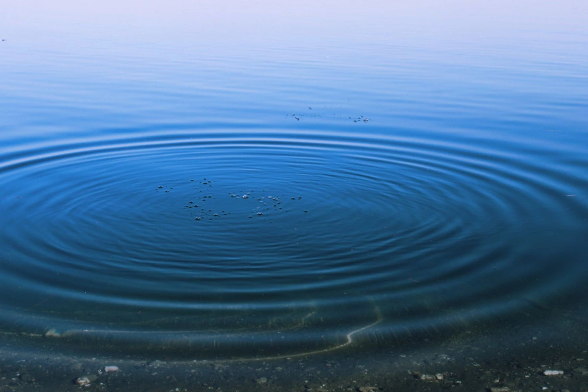 Ondas circulares concéntricas expandiéndose por la superficie azul del agua
