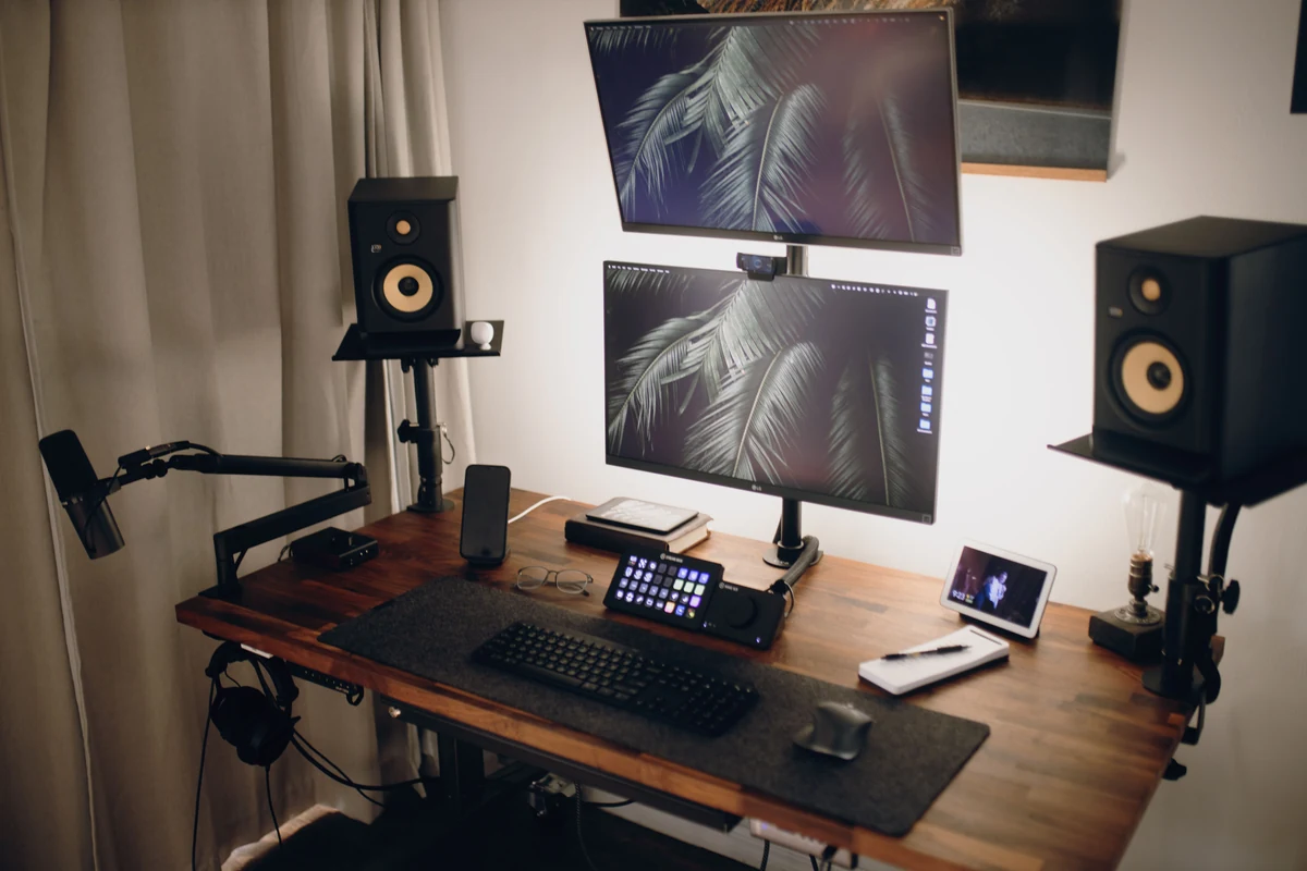 Dos altavoces de estudio sobre soportes a izquierda y derecha de un monitor en un escritorio de madera