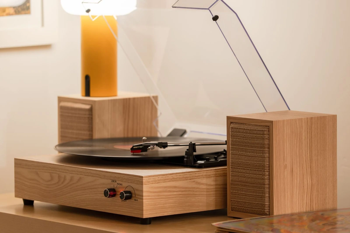 Tocadiscos de madera con la tapa abierta junto a dos altavoces de estantería sobre un mueble